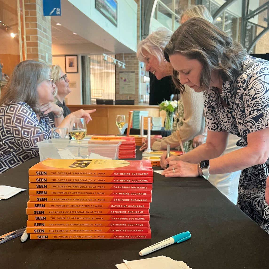 Readers having their copies of SEEN signed at a book table stacked with copies